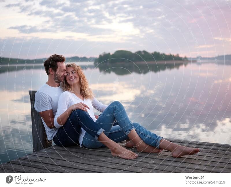 Romantic couple sitting on jetty at the lake smile Seated in the morning seasons spring season Spring Time springtime delight enjoyment Pleasant pleasure Secure