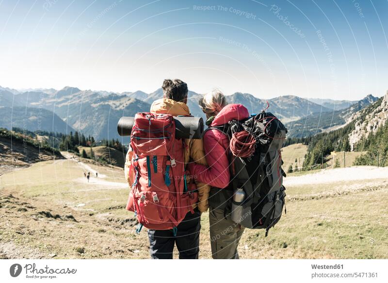 Austria, Tyrol, rear view of couple on a hiking trip in the mountains enjoying the view indulgence enjoyment savoring indulging View Vista Look-Out outlook