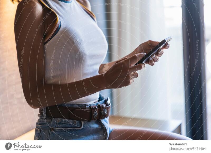 Young woman using smartphone females women Smartphone iPhone Smartphones midsection mid section Adults grown-ups grownups adult people persons human being