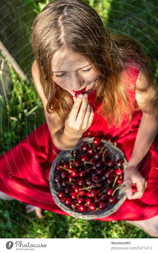 Girl sitting on a meadow eating cherries girl females girls Seated meadows Cherry Cherries child children kid kids people persons human being humans