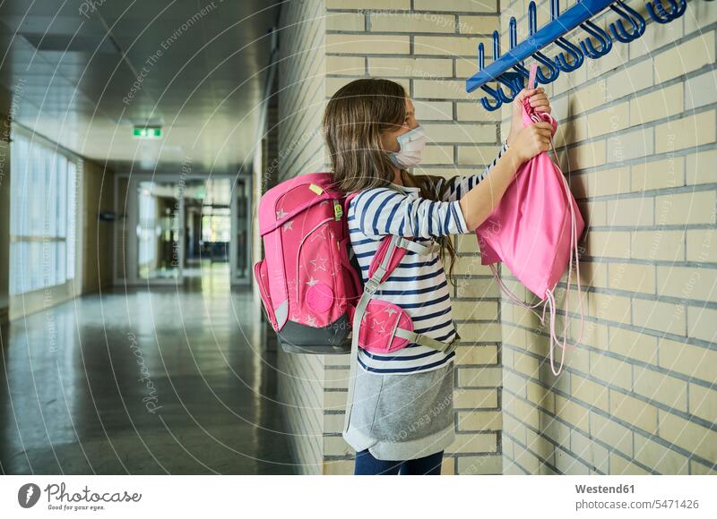 Girl wearing mask in school hanging up pouch pupils schoolchild schoolchildren colour colours Rosy stand healthy protect protecting safe Safety secure buildings