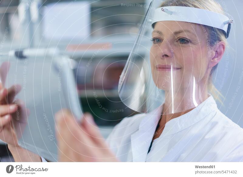 Mature female scientist wearing protective face shield while using digital tablet at laboratory color image colour image indoors indoor shot indoor shots