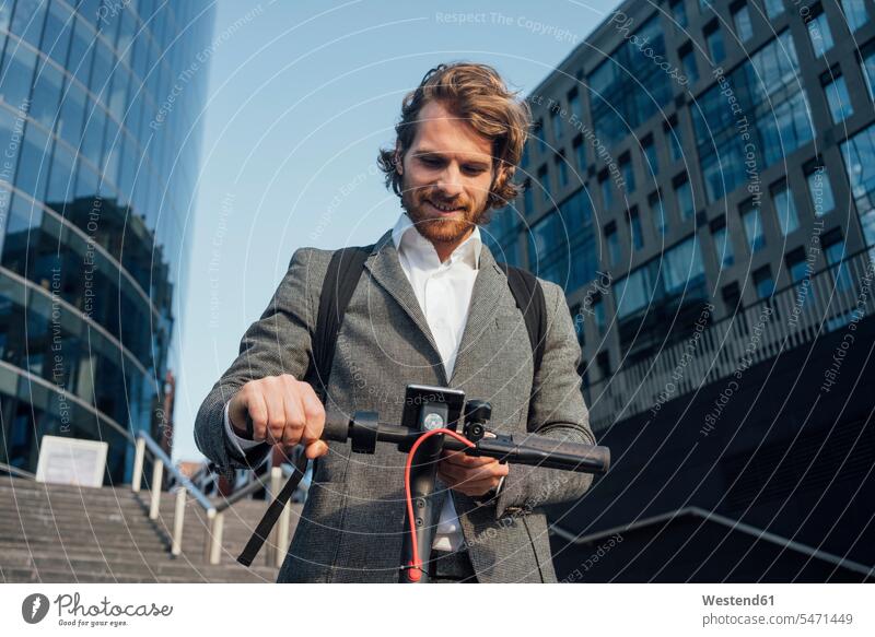 Male entrepreneur using mobile phone while standing with electric push scooter at downtown color image colour image outdoors location shots outdoor shot