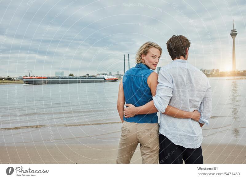 Germany, Duesseldorf, affectionate young couple at Rhine riverbank Affection Affectionate River Rivers twosomes partnership couples riverside water waters