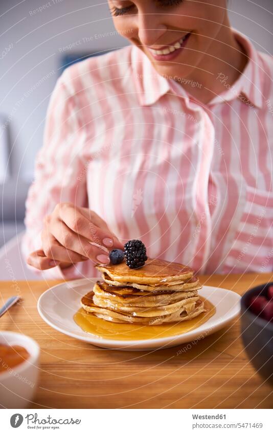 Young woman garnishing fresh pancakes with berries maple sirup maple syrup Freshness blackberry blackberries blackberry fruit blueberry bilberry blueberries