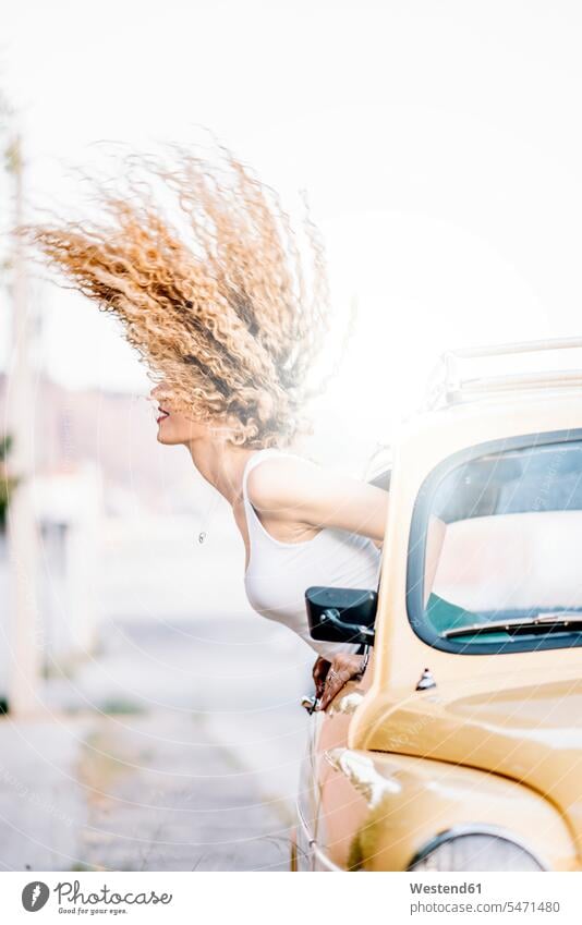 Young woman leaning out of car window tossing her hair hair toss Tossing Hair females women car windows people persons human being humans human beings Adults