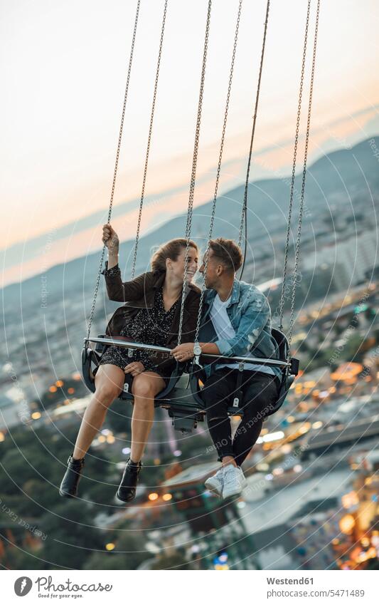 Young couple in love, riding chairoplane on a fairground young couple young couples young twosome young twosomes romance Romancing kissing kisses funfairs