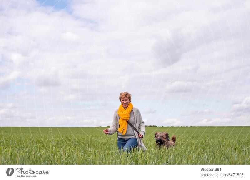 Happy woman going walkies with dog in a field human human being human beings humans person persons celibate celibates singles solitary people solitary person