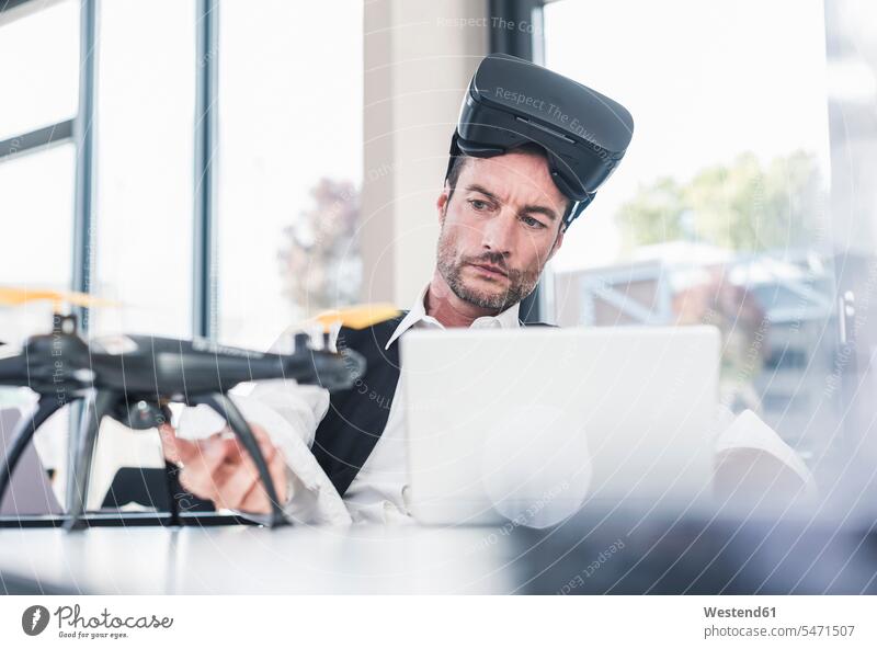 Businessman sitting in office working on a drone, using VR glasses drones Development developing Developments At Work using laptop using a laptop Using Laptops