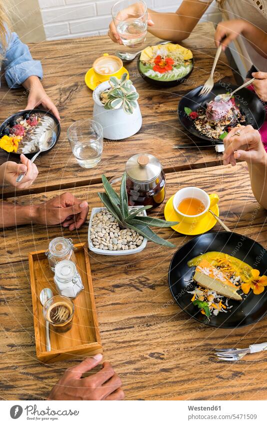 People gathering around wooden table eating and drinking various food different wood table group of people Group groups of people Table Tables persons