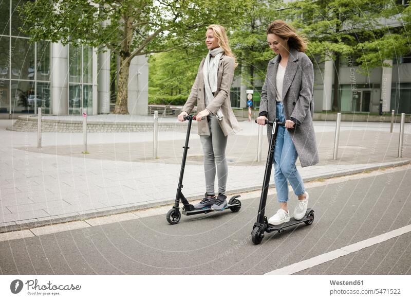 Young women riding electric scooters in the street human human being human beings humans person persons caucasian appearance caucasian ethnicity european 2