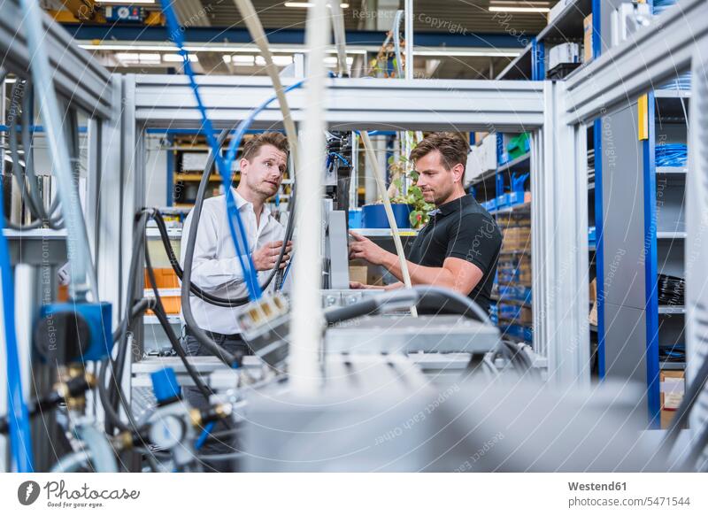 Two men having a meeting at a machine in factory colleague Occupation Work job jobs profession professional occupation business life business world