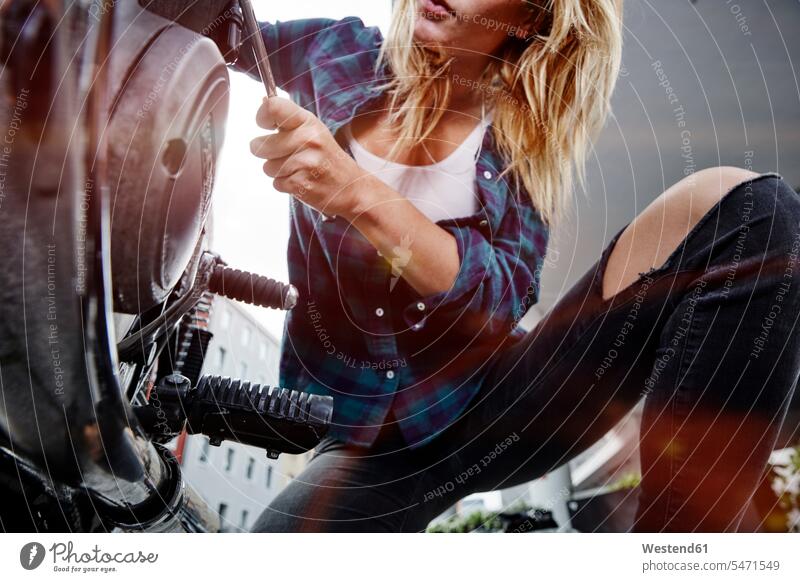 Young woman working on motorcycle motorbike Motor Cycle At Work females women motor vehicle road vehicle road vehicles motor vehicles transportation Adults