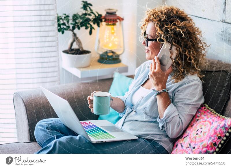 Woman on couch at home with coffee mug, laptop and cell phone dyed hair Curtain Curtains Drapery Draperies cozy sociable comfortable cosy content pleased