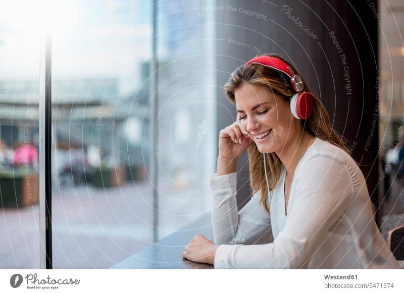 Happy young woman listening to music with headphones happiness happy females women hearing headset Adults grown-ups grownups adult people persons human being