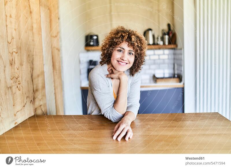 Portrait of smiling woman leaning on wooden table females women wood table smile portrait portraits Adults grown-ups grownups adult people persons human being