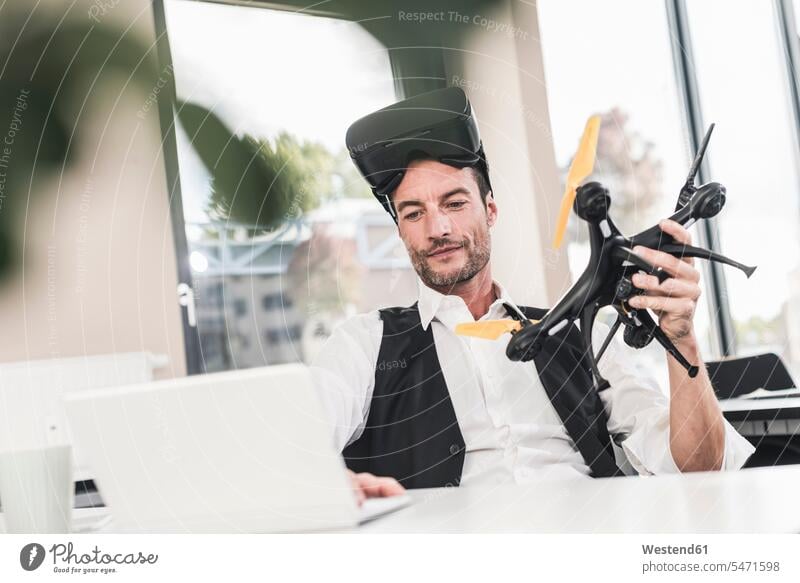 Businessman sitting in office working on a drone, using VR glasses Development developing Developments using laptop using a laptop Using Laptops