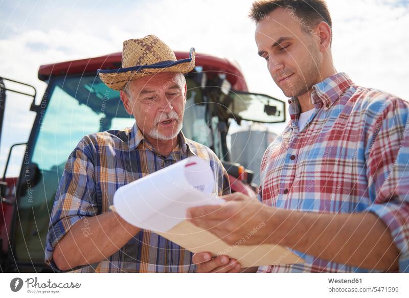 Two farmers discussing data from clipboard on the farm clipboards clip-board clip-boards clip board discussion agriculturists agriculture checking Test testing