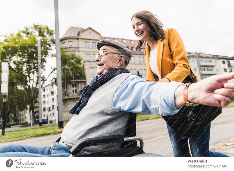 Laughing young woman pushing happy senior man in wheelchair human human being human beings humans person persons caucasian appearance caucasian ethnicity