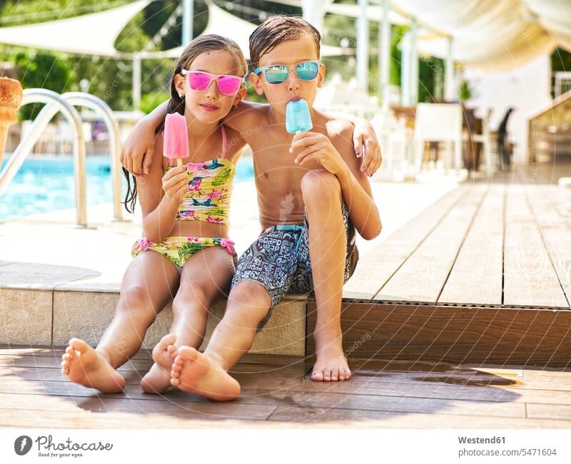 Portrait of little girl and boy with popsicles wearing mirrored sunglasses in front of swimming pool human human being human beings humans person persons