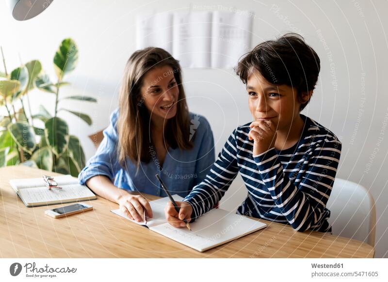 Female tutor helping boy in writing homework at home color image colour image Spain casual clothing casual wear leisure wear casual clothes Casual Attire