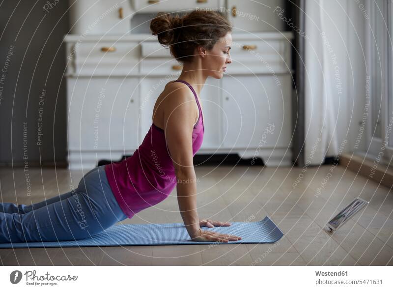 Mid adult woman watching digital tablet while doing yoga at home color image colour image indoors indoor shot indoor shots interior interior view Interiors day
