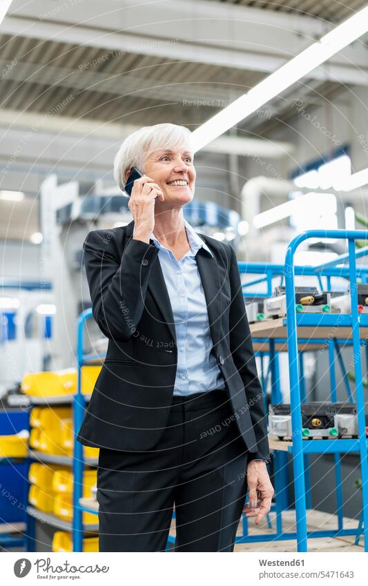 Smiling senior businesswoman on cell phone in a factory factories on the phone call telephoning On The Telephone calling businesswomen business woman