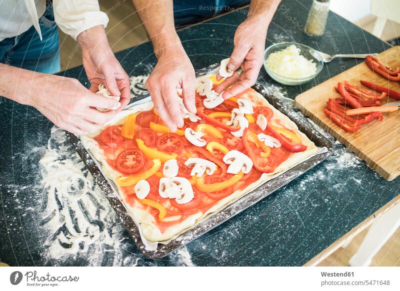 Close-up of couple preparing a pizza in kitchen at home twosomes partnership couples Food Preparation preparing food Pizza Pizzas people persons human being