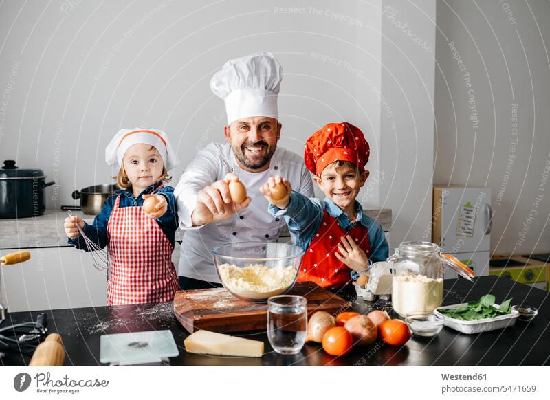 Portrait of father with two kids preparing dough in kitchen at home Chefs cook cooks Bowls hold learn smile delight enjoyment Pleasant pleasure Cheerfulness