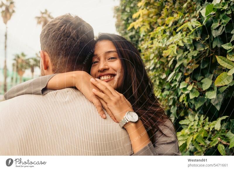 Smiling woman embracing man while standing by leaves at park color image colour image outdoors location shots outdoor shot outdoor shots day daylight shot