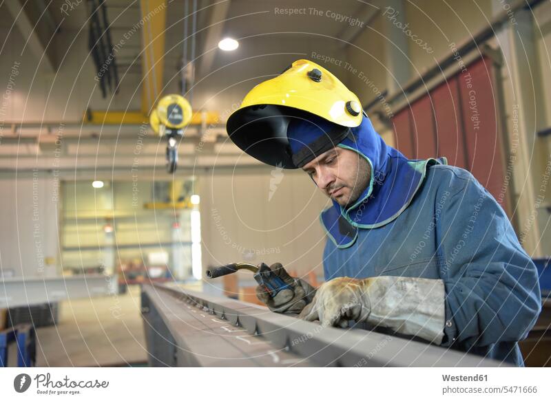 Welder checking metal surface in factory factories working At Work scrutiny scrutinizing surfaces welder metals industry industrial man men males welding