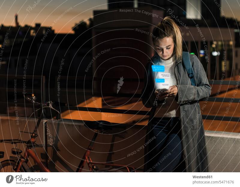 Young woman outdoors at night with text emerging from smartphone by night nite night photography Smartphone iPhone Smartphones emerge females women mobile phone