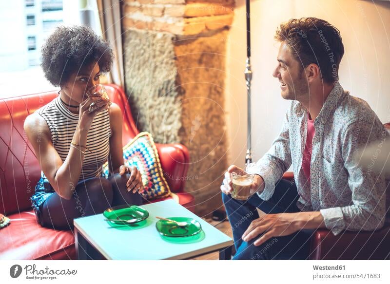 Smiling man looking at girlfriend drinking coffee while sitting in cafe color image colour image indoors indoor shot indoor shots interior interior view