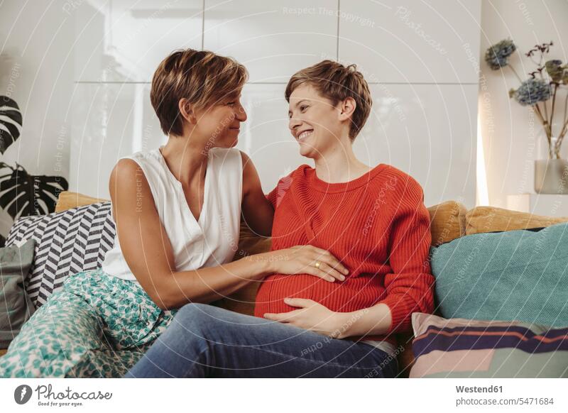 Happy lesbian couple touching belly of the expectant mother pregnant Pregnant Woman twosomes partnership couples happiness happy bellies abdomen human abdomen