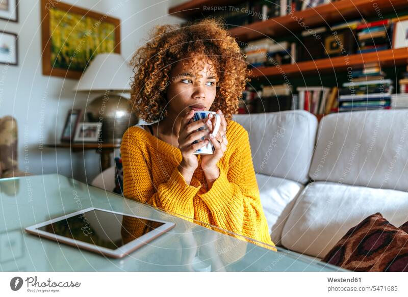 Young woman with curly hair holding mug at home curls curled mugs cup females women people persons human being humans human beings Adults grown-ups grownups