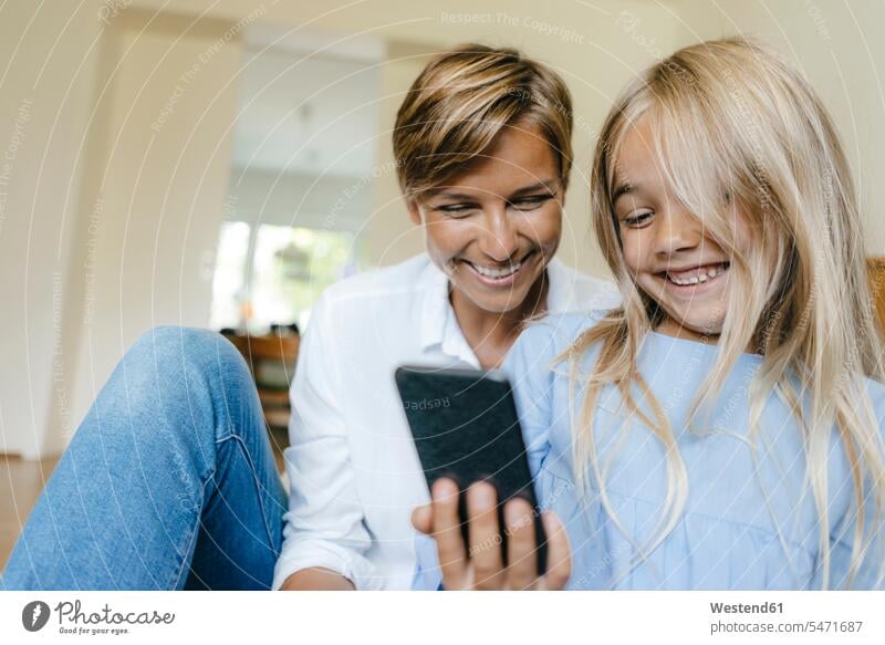 Happy mother and daughter looking at smartphone together happiness happy daughters eyeing Smartphone iPhone Smartphones mommy mothers mummy mama home at home