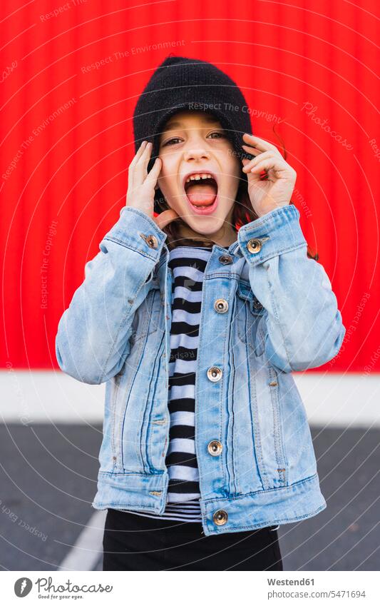 Portrait of screaming little girl wearing denim jacket and black cap hats caps mouth open open mouth casual leisure wear casual clothing casual wear