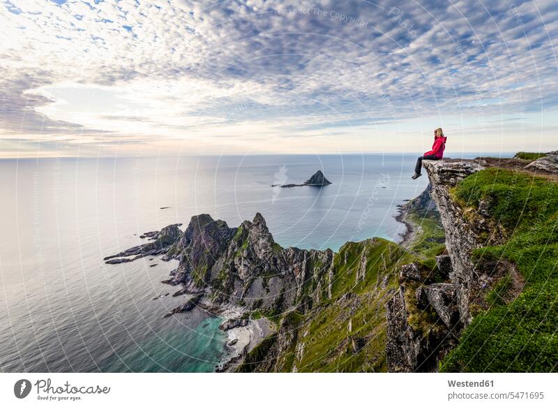 Explorer admiring view while sitting on Matind mountain at Andoya, Norway color image colour image outdoors location shots outdoor shot outdoor shots sunset