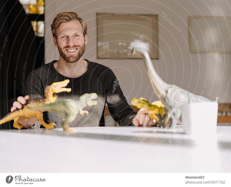 Portrait of smiling man with toy dinosaurs on table human human being human beings humans person persons caucasian appearance caucasian ethnicity european 1