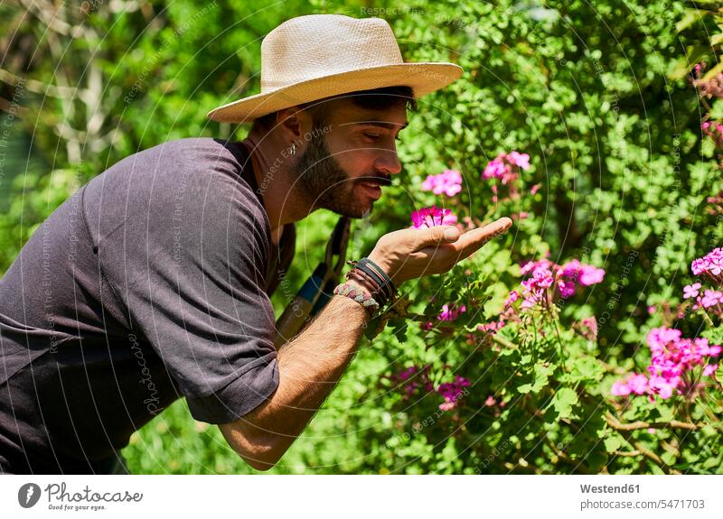 Man smelling flowers in garden gardeners At Work work hold smile seasons summer time summertime summery relax relaxing relaxation delight enjoyment Pleasant