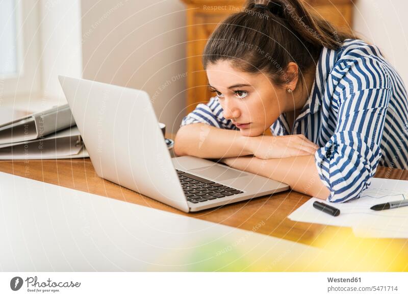 Young woman looking at laptop on desk at home Laptop Computers laptops notebook eyeing females women computer computers view seeing viewing Adults grown-ups