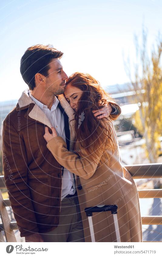 Businessman embracing girlfriend on elevated walkway at airport color image colour image outdoors location shots outdoor shot outdoor shots day daylight shot