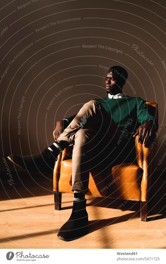 Man sitting in leather armchair looking sideways human human being human beings humans person persons African black black ethnicity coloured 1 one person only