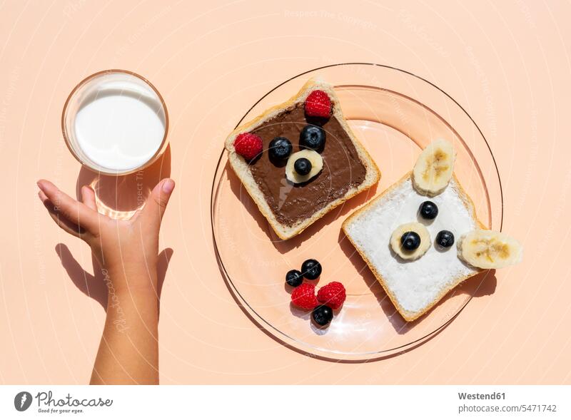 Studio shot of toasts with bear faces made of fruits and hand of baby girl reaching for glass of milk studio shot studio photograph studio photographs