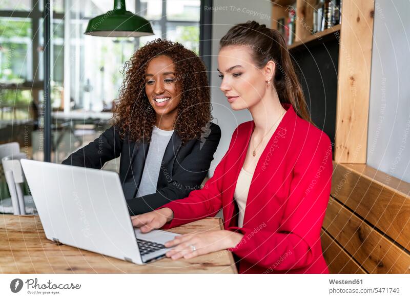 Businesswomen looking at laptop in office cafeteria color image colour image indoors indoor shot indoor shots interior interior view Interiors day daylight shot