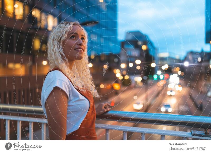 Young woman in the city at dusk with urban street in London smile in the evening delight enjoyment Pleasant pleasure happy Contented Emotion pleased free