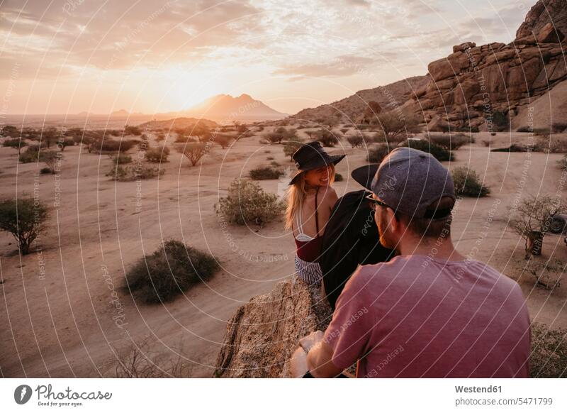 Namibia, Spitzkoppe, friends sitting on a rock at sunset Seated rocks sunsets sundown friendship atmosphere atmospheric mood moody Atmospheric Mood Vibe Idyllic