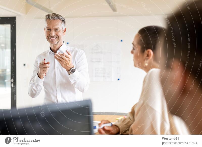 Smiling mature businessman leading a meeting in office human human being human beings humans person persons caucasian appearance caucasian ethnicity european