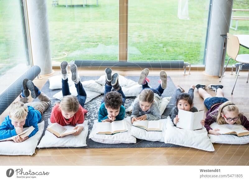 Pupils lying on the floor reading books in school break room floors laying down lie lying down schools student pupils schoolchildren education leisure free time