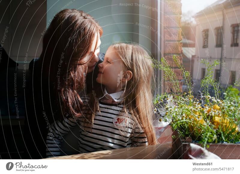 Smiling girl with her mother in a cafe windows pane panes window glass window glasses Window Pane windowpanes smile Seated sit Secure happy closeness